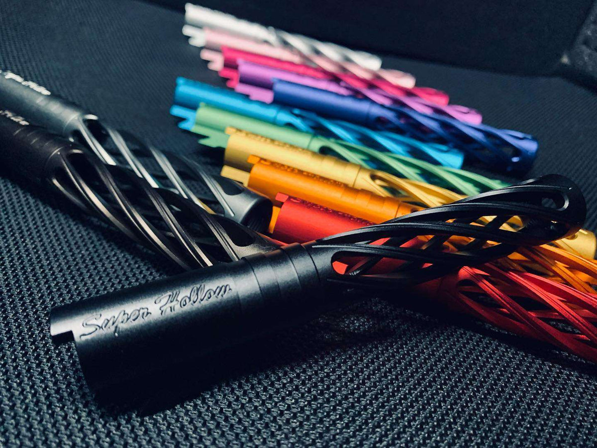 Close-up of a black Dr. Black Super Hollow outer barrel in the foreground, engraved with Super Hollow, surrounded by multiple colour variants fanned out on a textured surface.