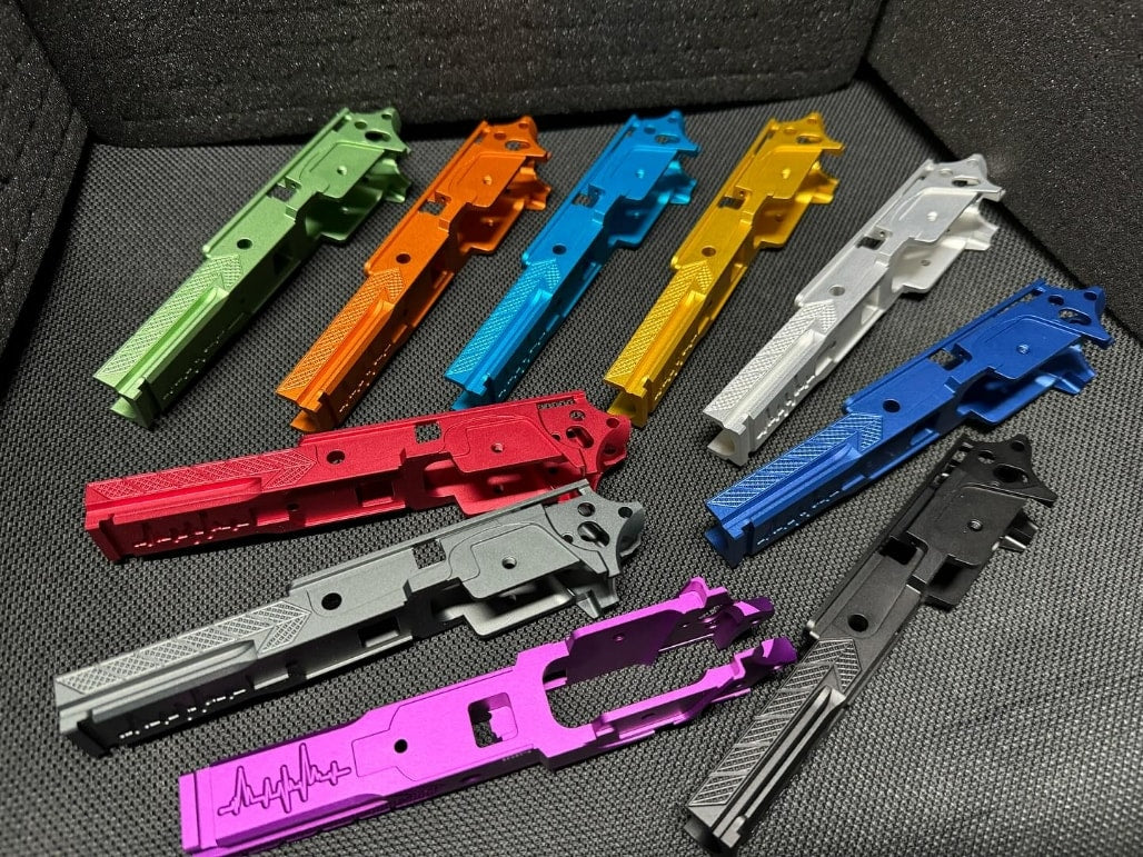 Nine Ball aluminum Hi-Capa frames with compensator laid out in ten anodized colors including green, orange, blue, gold, silver, dark blue, black, red, grey, and purple.